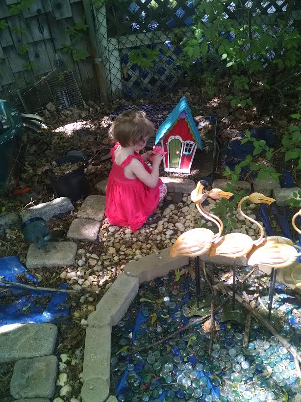 small girl playing in backyard garden